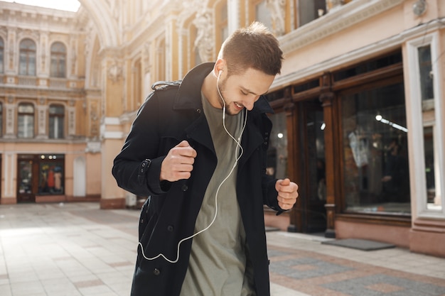 ヘッドフォンで音楽を聴いて踊る陽気な若者。