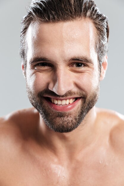 Young cheerful man standing isolated over grey wall