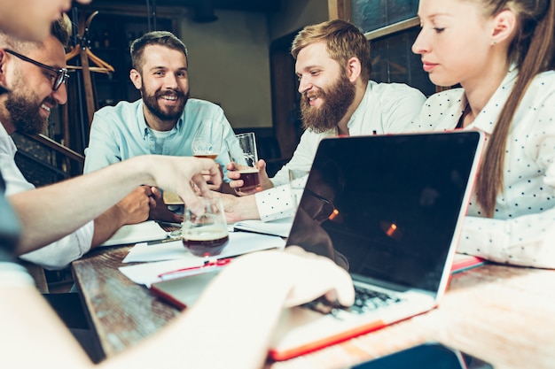 Young cheerful people smile and gesture while relaxing in pub