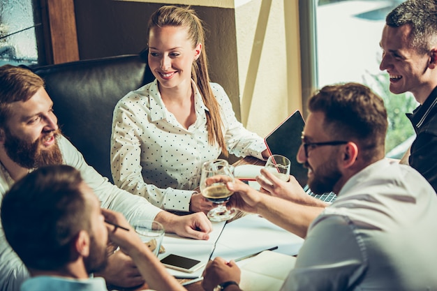 Young cheerful people smile and gesture while relaxing in pub