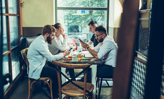 Young cheerful people smile and gesture while relaxing in pub.