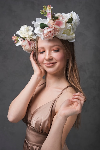 Young cheerful romantic woman in dress with beautiful flower wreath