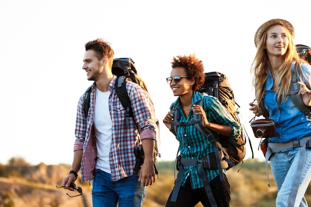 Young cheerful travelers with backpacks smiling, walking in canyon