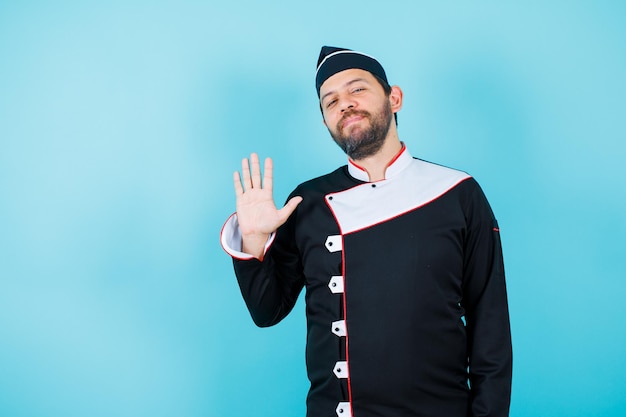 Foto gratuita il giovane chef sta mostrando cinque gesti su sfondo blu