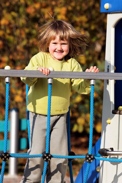 Маленький ребенок играет на красочной детской площадке осенью