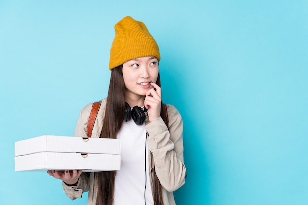 ピザ​を​保持している​若い​中国人​女性​は​、​コピー​スペース​を​見て​何​か​について​リラックスした​思考​を​分離しました​。