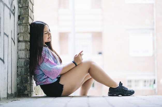 Free photo young chubby caucasian lady sitting outdoors using her smartphone