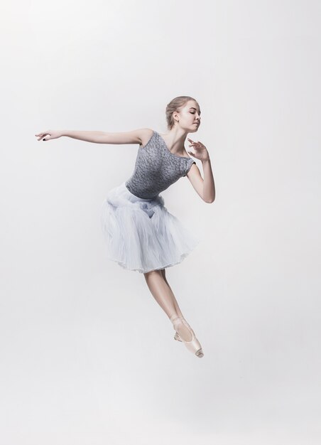白い背景の上で踊って若いクラシックダンサー。バレリーナプロジェクト。
