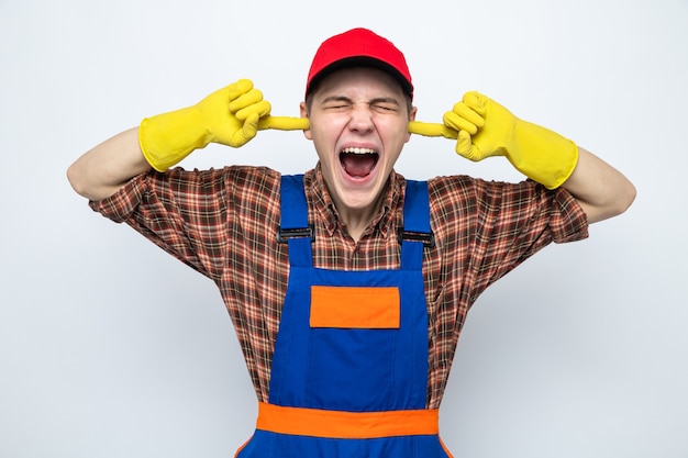 Young cleaning guy wearing uniform and cap isolated on white wall