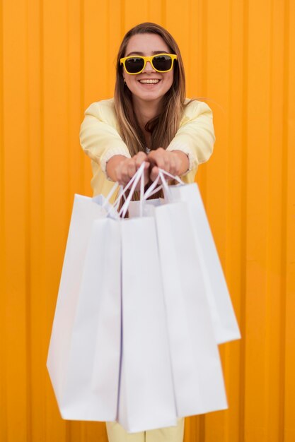 彼女の買い物袋を示す黄色の服を着ている若いクライアント