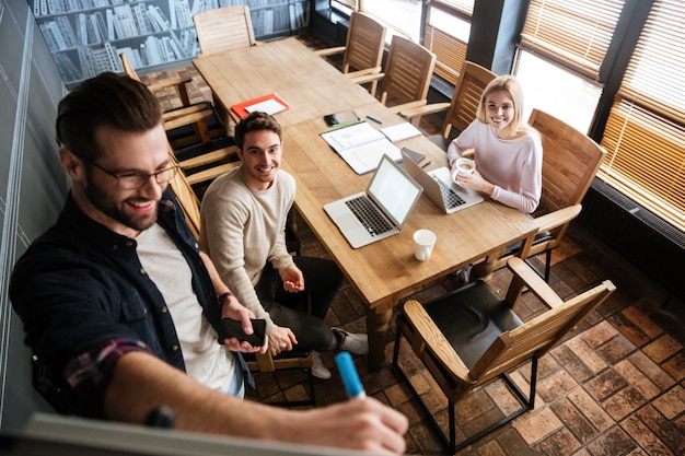 Young colleagues sitting while work with laptops and desk