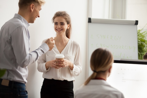 Young colleagues talking laughing at coffee break in coworking office