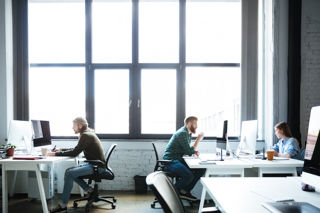 Young colleagues work in office using computers.