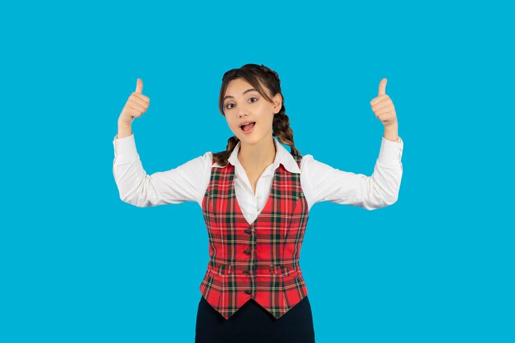制服を着て親指を立てる若い女子大生。高品質の写真