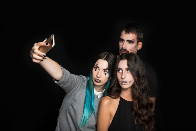 Young company with creepy makeup taking selfie