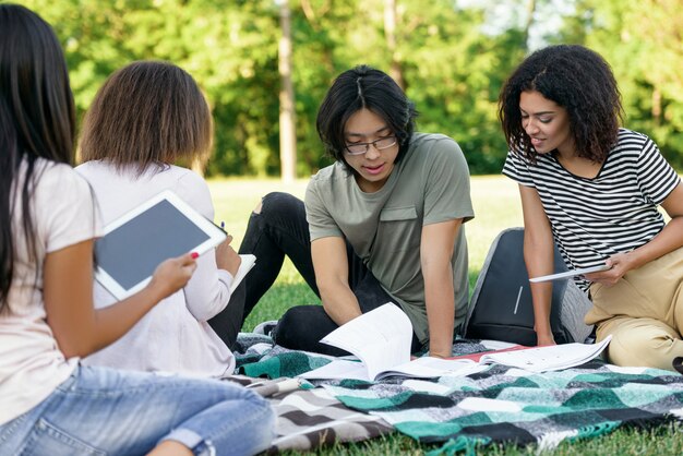 Молодые сосредоточены студенты, обучающиеся на открытом воздухе.