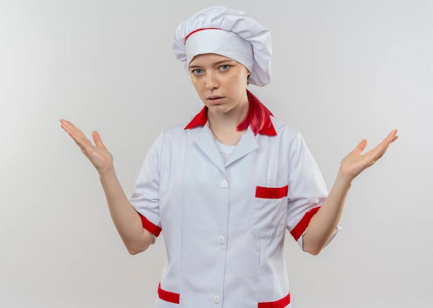 Young confident blonde female chef in chef uniform holds hands up isolated on white wall