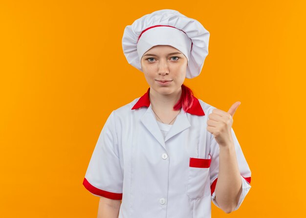 Free photo young confident blonde female chef in chef uniform thumbs up isolated on orange wall