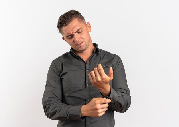 Young confident blonde handsome man fastens button on his sleeve isolated on white background with copy space