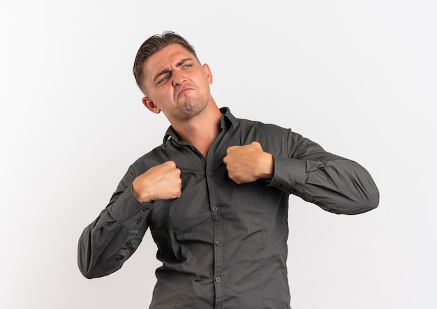 Free photo young confident blonde handsome man holds fists together isolated on white background with copy space