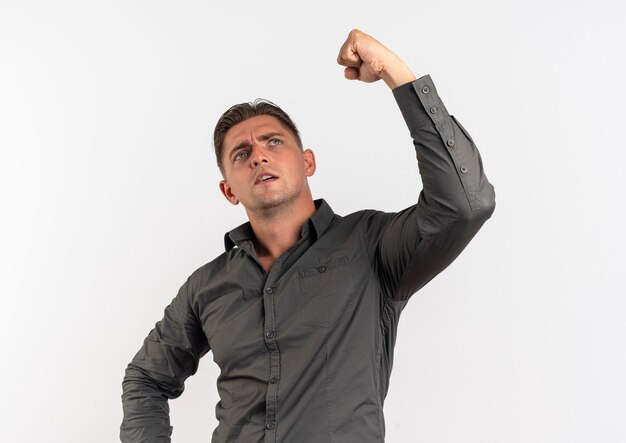 Young confident blonde handsome man raises fist up and looks up isolated on white background with copy space