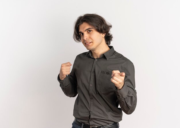 Молодой уверенный в себе красивый кавказский мужчина держит кулак и указывает на камеру, изолированную на белом фоне с копией пространства