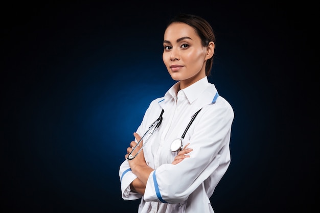 Young confident lady doctor in medical gown looking
