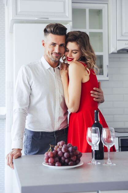 Young confident man hug his girlfriend in red dress