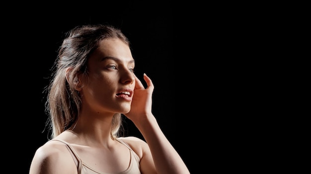 Foto gratuita giovane modella fiduciosa che usa crema per il viso in una pubblicità di bellezza