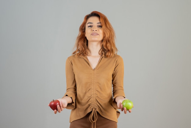 Young confident redhead holding organic fresh apples .