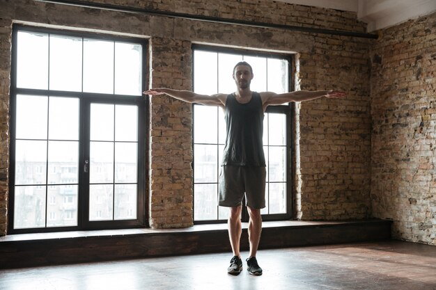 Young confident sportsman warming up at the gym