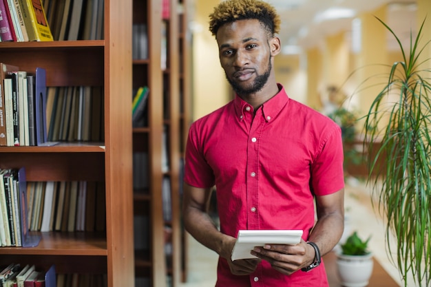 Foto gratuita giovane studente fiducioso nella biblioteca