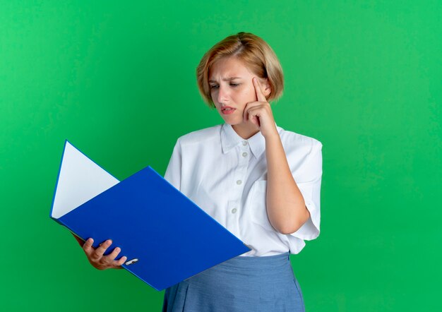 young confused blonde russian girl holds and looks at file folder