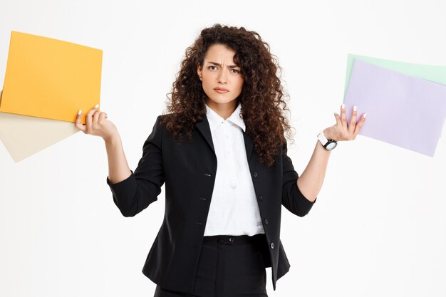 Young confused curly girl holding documents
