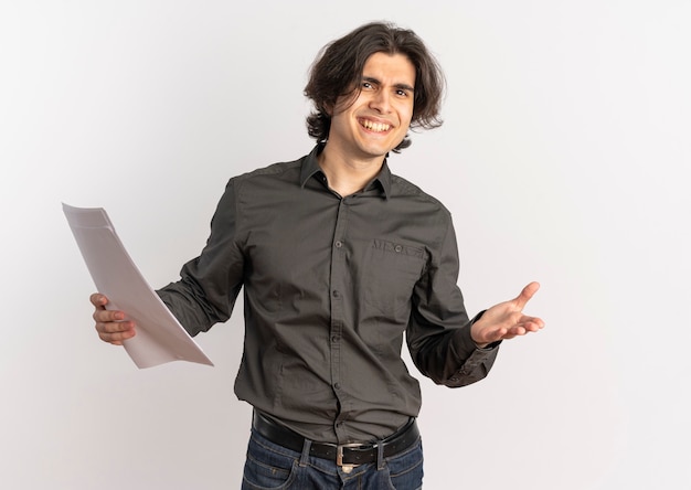Young confused handsome caucasian man holds blank white paper sheets and looks at camera isolated on white background with copy space