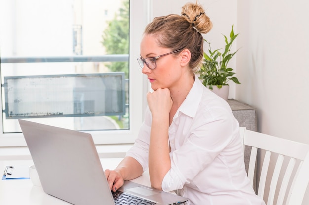 Young contemplated businesswoman looking at laptop