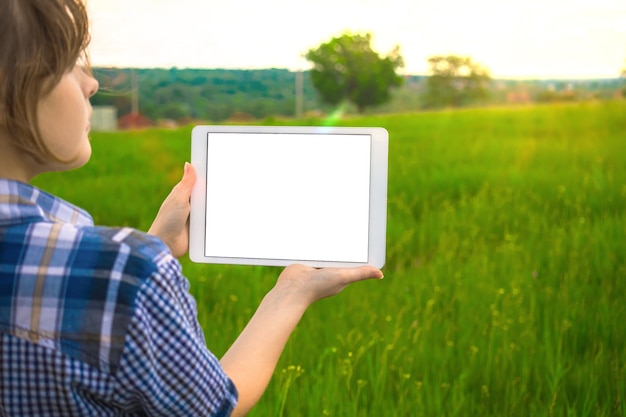 A young contractor develops a construction plan concept, young girl hold tablet screen with mockup, firld natue background, copy space photo