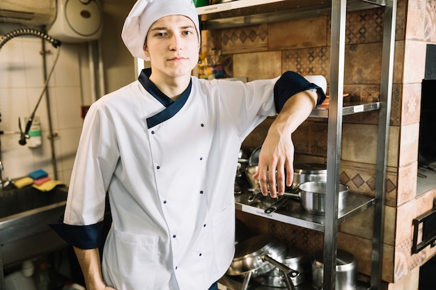 Giovane cuoco in piedi in cucina