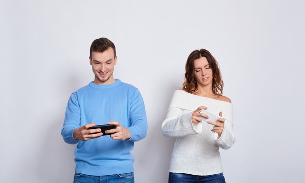 携帯​電話​で​ビデオ ゲーム​を​する​若い​カップル​。