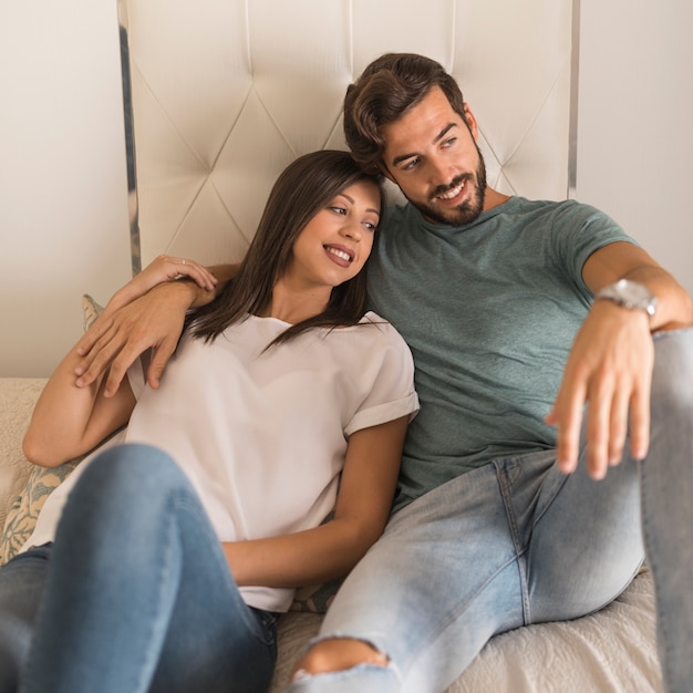 Young couple on bed looking away