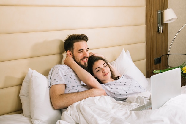 Young couple in bed using laptop