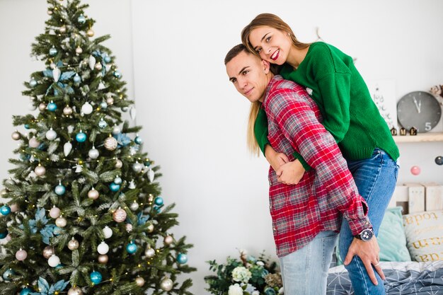 Young couple in bedroom next to christmas tree