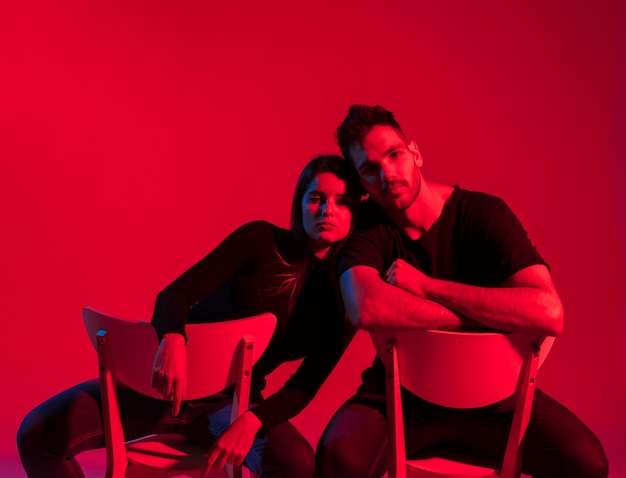 Young couple in black clothes sitting on chairs