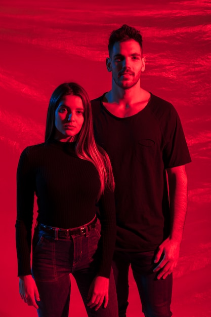 Young couple in black standing on red background 