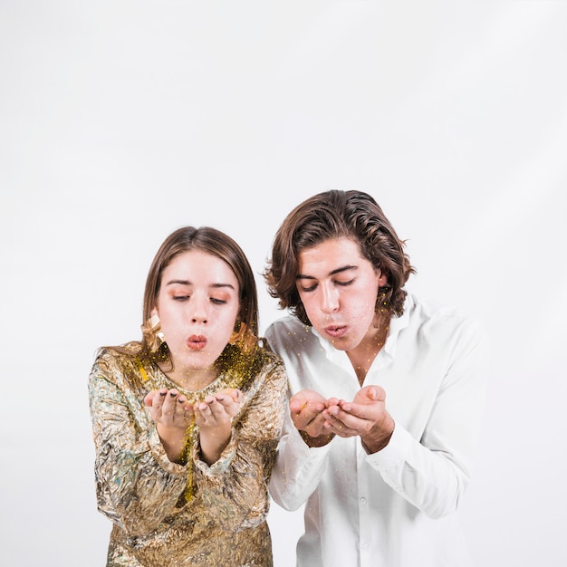 Free photo young couple blowing sparkles