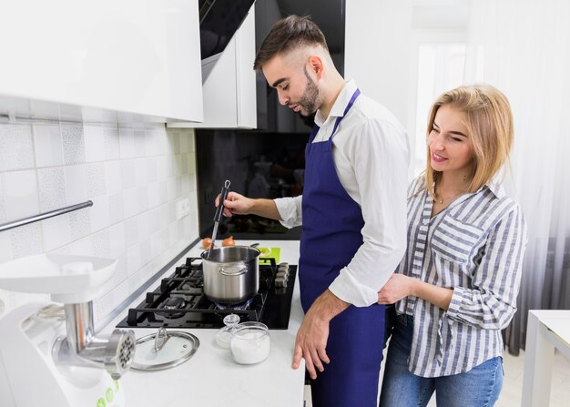 Young couple boiling water in pot on stove 