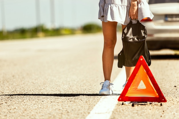 The young couple broke down the car while traveling on the way to rest. They are trying to stop other drivers and ask for help or hitchhike. Relationship, troubles on the road, vacation.