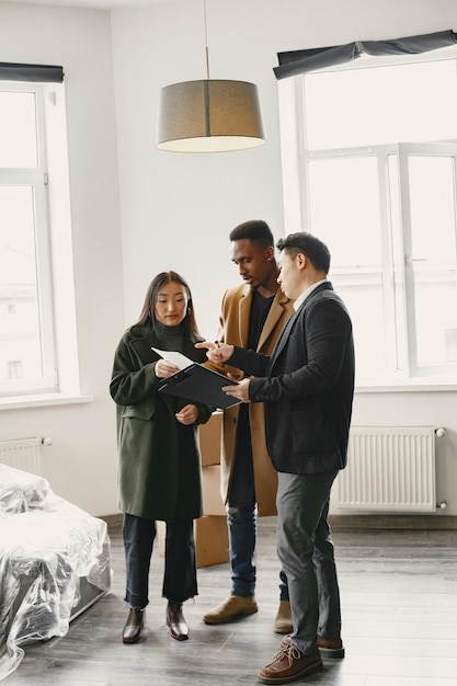 Молодая пара покупает новый дом. Азиатская женщина и африканский мужчина. Подписание документов в новом доме.