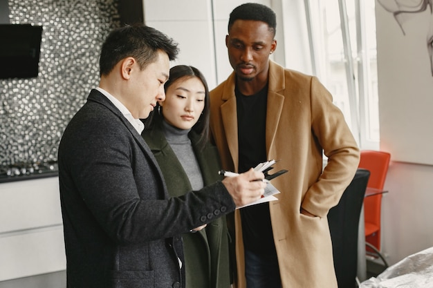 Young Couple Buying A New House. Asian woman and African man. Signing documents at new home.