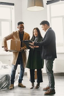 Young couple buying a new house. asian woman and african man. signing documents at new home.